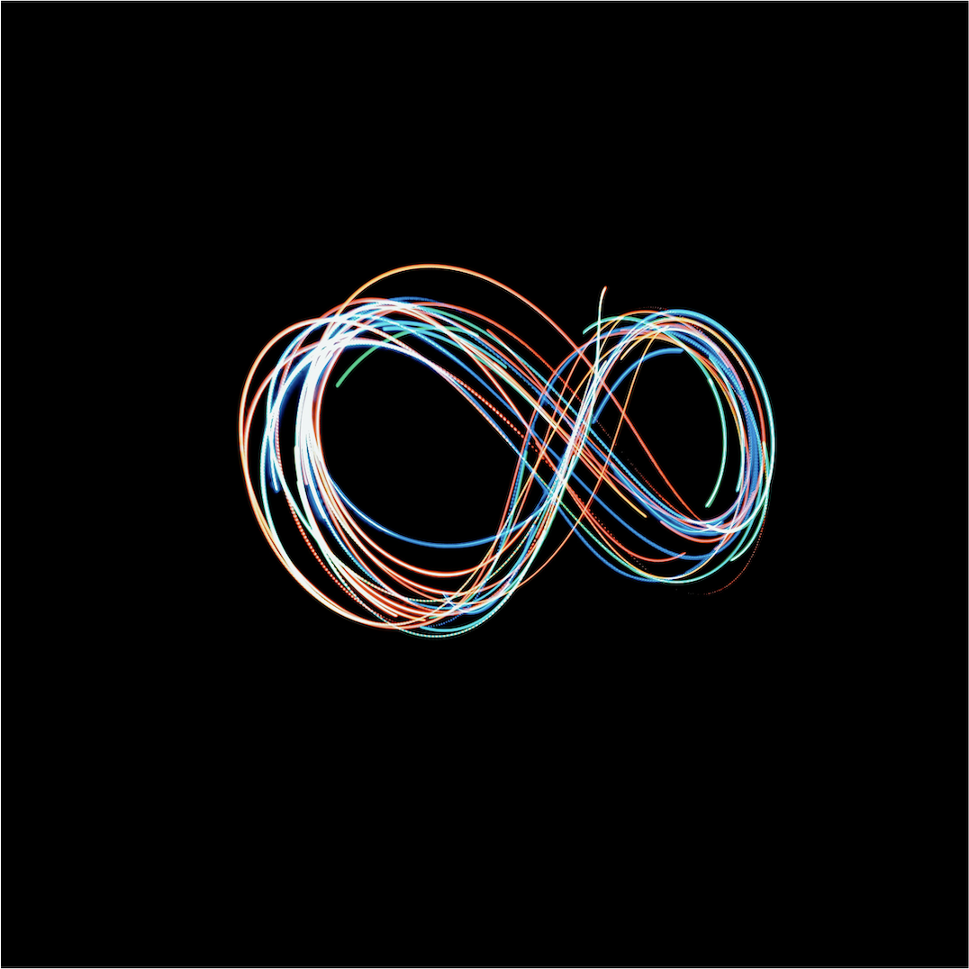 Long-exposure light painting photograph of an infinity symbol formed by flowing streaks of multicolored light — red, orange, blue, cyan, white, and green — overlapping in looping curves against a pure black background, representing the infinite creator loop